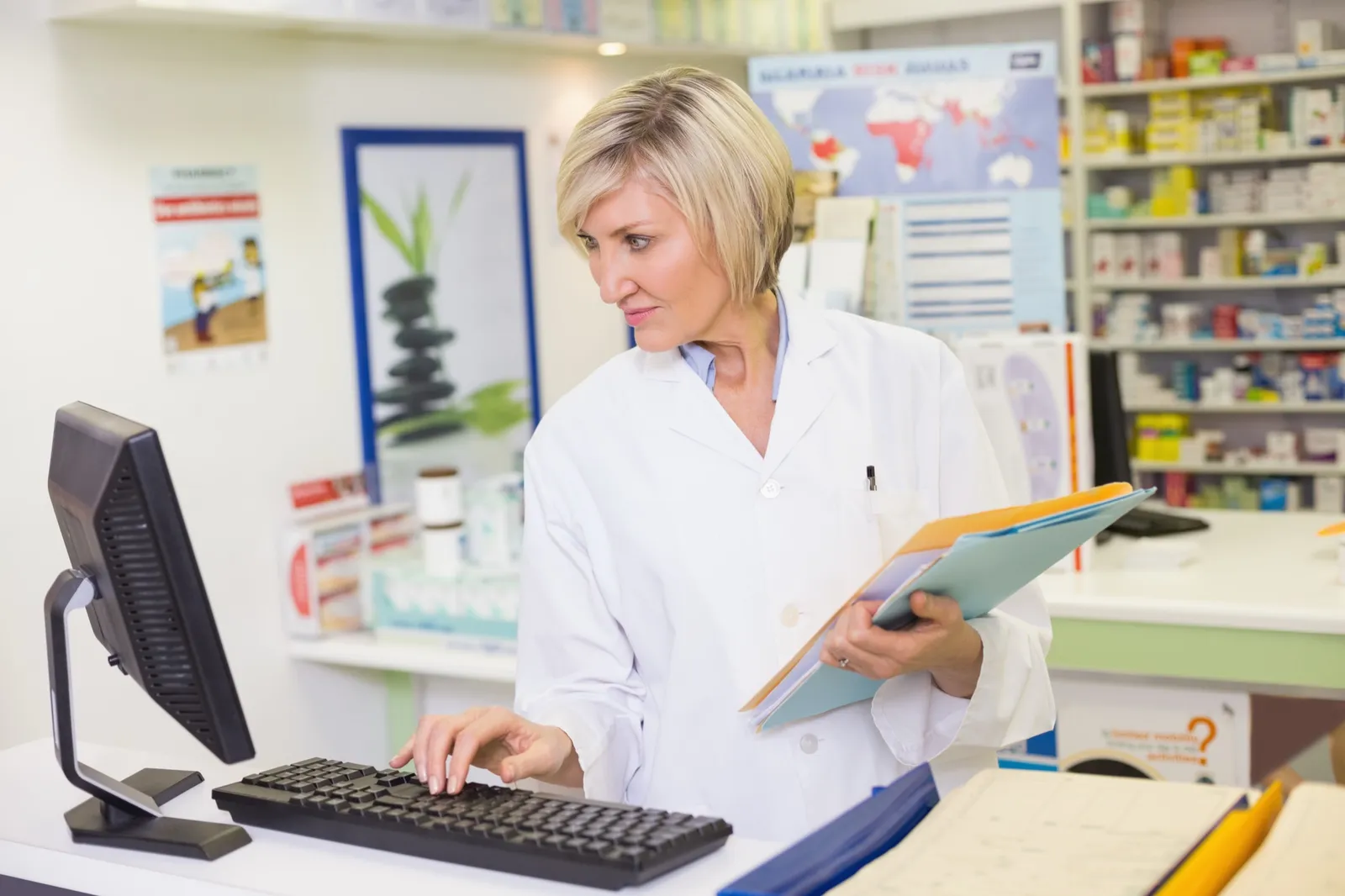Pharmacist working in the pharmacy management system at a computer