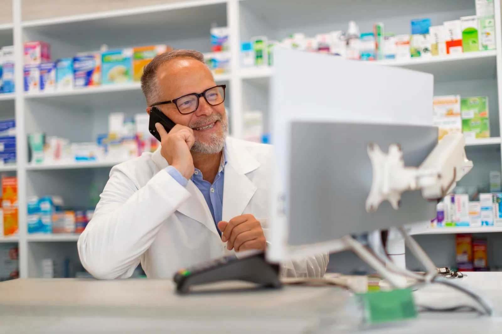 Pharmacist on the phone with support while working at a pharmacy computer